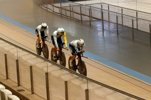 Free Professional cyclists in team uniforms racing on an indoor velodrome track. Stock Photo