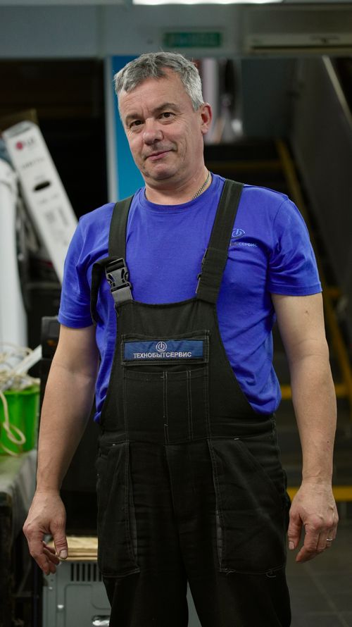 Free Middle-aged man in work overalls standing in an industrial workshop setting. Stock Photo