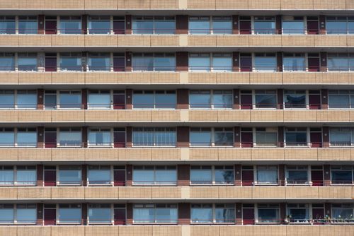 Free A symmetrical view of an apartment building facade with multiple windows and balconies. Stock Photo