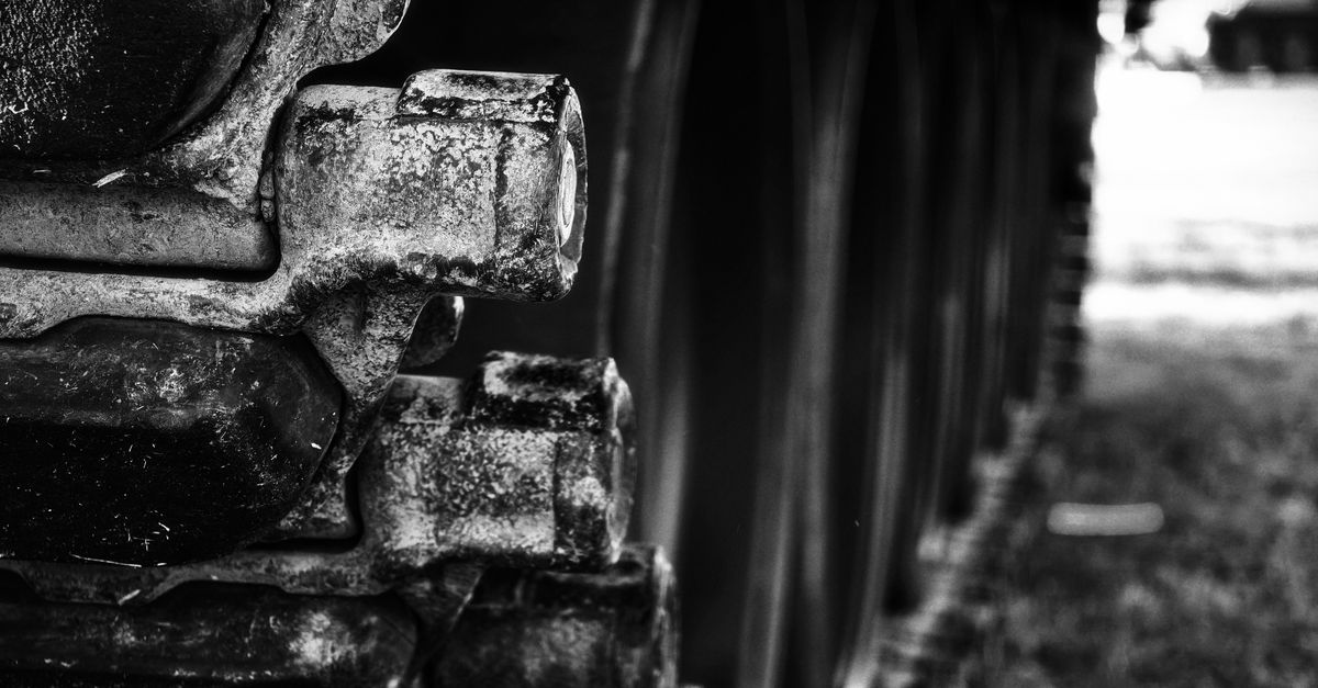 Artistic black and white photo showcasing the weathered details of vintage tank tracks.