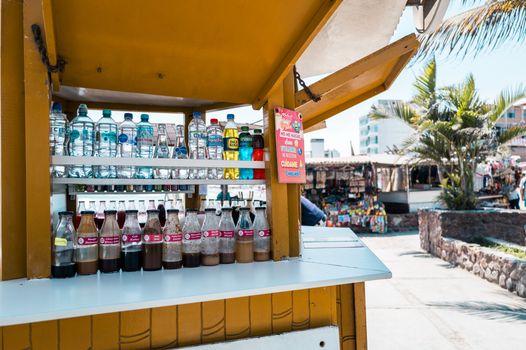 A colorful assortment of beverages on display at a market stall in Huanchaco, Peru, under a bright sunny day.