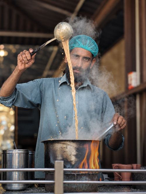 Free A street vendor energetically preparing a steaming cup of chai in Karachi, showcasing traditional tea-making skills. Stock Photo