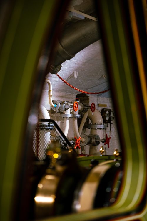 Free Close-up view of an industrial pipe system with red valves in a dimly lit environment. Stock Photo