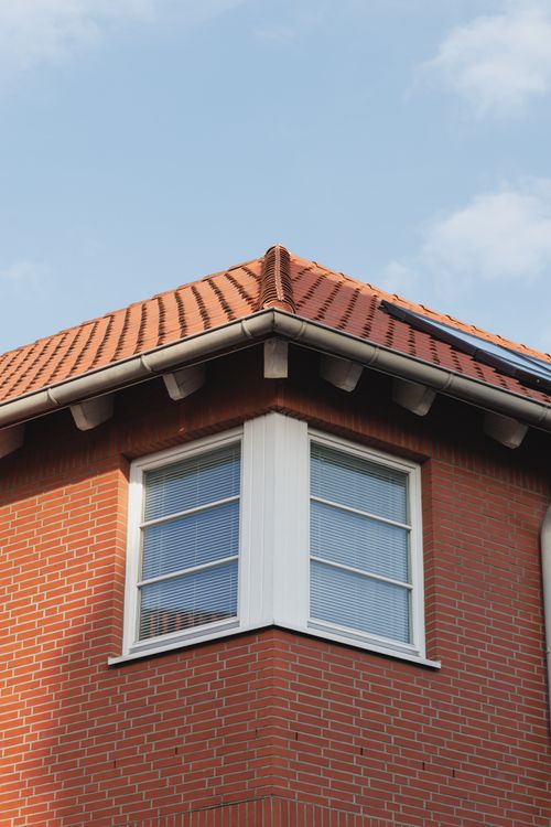 Free A charming red brick house in Hildesheim, featuring a gable roof and white windows under a clear blue sky. Stock Photo