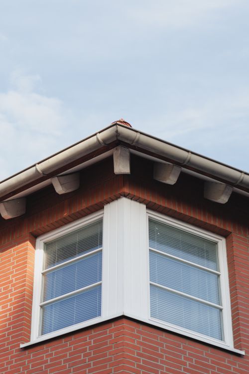 Free Close-up of a brick house corner with windows against a blue sky in Hildesheim, Germany. Stock Photo