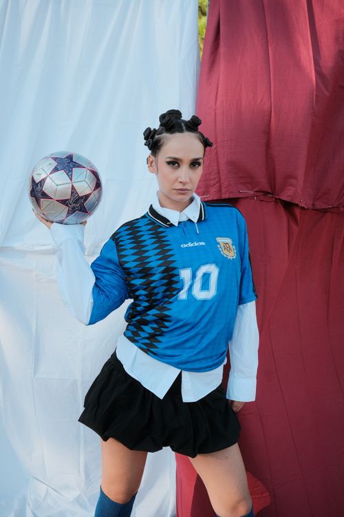 Free Confident athlete in blue jersey holding soccer ball against a vibrant backdrop. Stock Photo