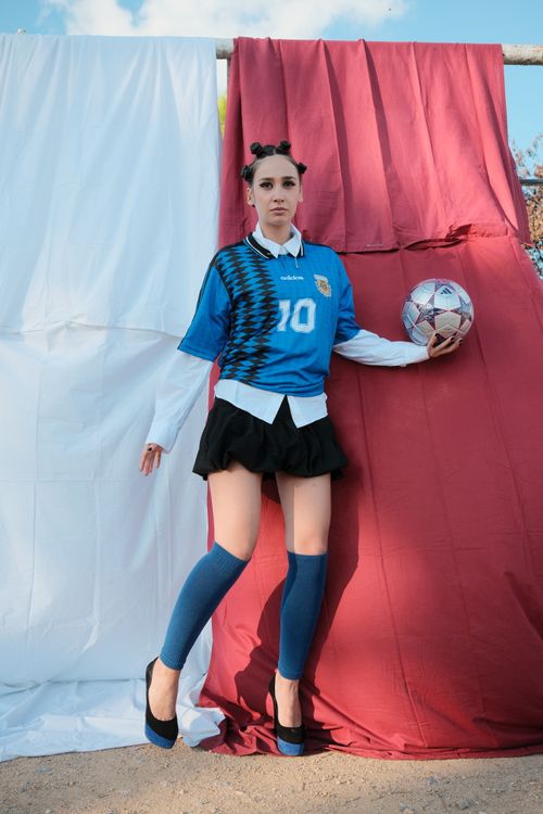 Free A young woman stands confidently holding a soccer ball, wearing a blue jersey. Stock Photo