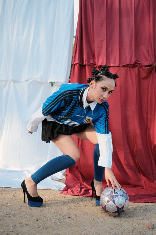 Free Creative soccer-inspired fashion photoshoot featuring a stylish model outdoors. Stock Photo