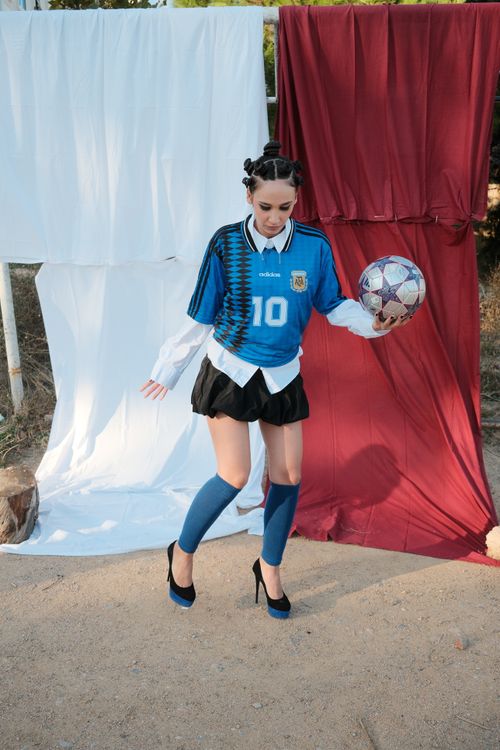 Free Woman in fashionable soccer attire holding a metallic soccer ball outdoors. Stock Photo