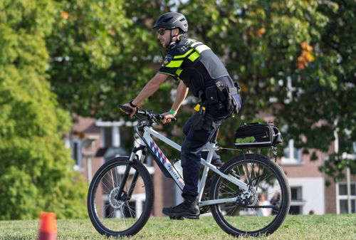 Free A police officer in uniform patrolling a city street on a bicycle during the day. Stock Photo