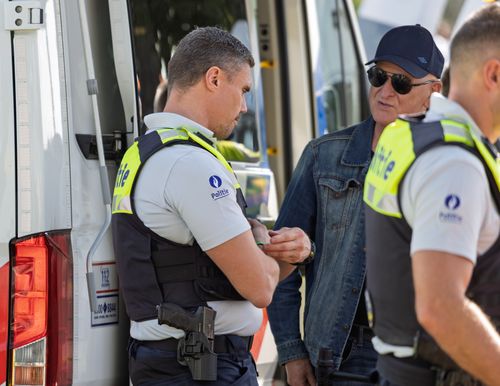 Free Police officers in uniform discussing near a van during daylight. Stock Photo