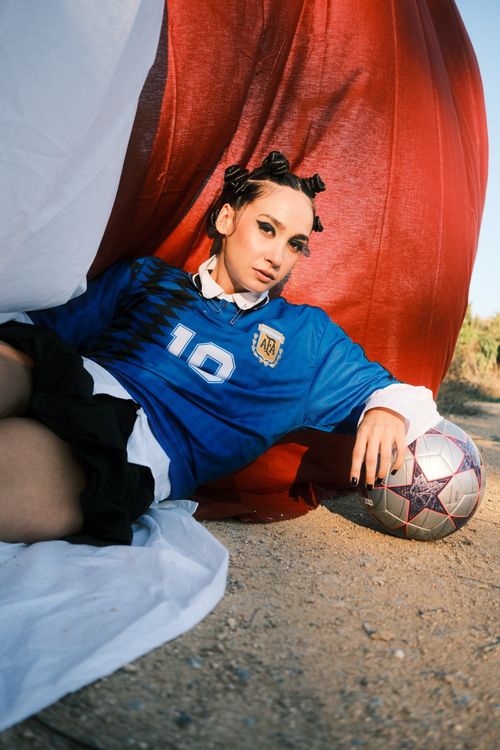 Free Young woman in blue jersey with soccer ball in outdoor setting. Stock Photo