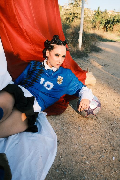 Free A person poses outdoors in a blue soccer jersey with a ball, showcasing style and sport. Stock Photo