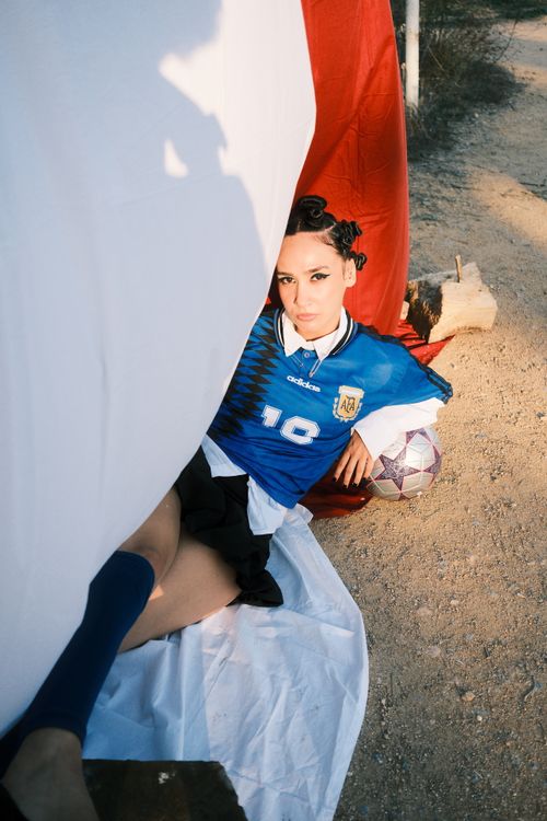 Free A woman in a blue Argentina soccer jersey poses with a ball on a sunny day. Stock Photo