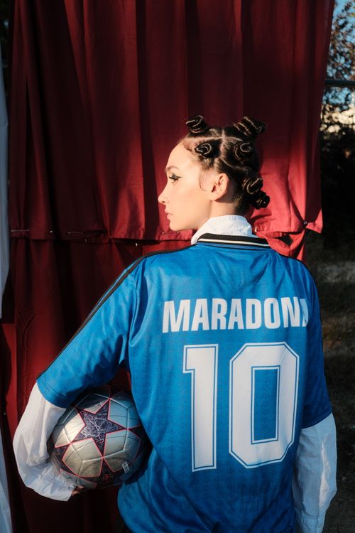 Free A person in a blue Maradona soccer jersey holding a football outdoors. Stock Photo