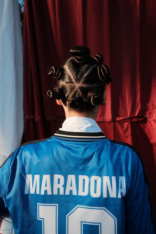 Free A person wearing a Maradona jersey, viewed from behind, featuring an intricate hairstyle. Stock Photo
