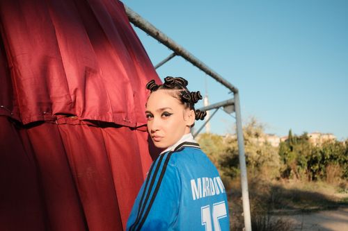Free Outdoor portrait of woman in blue jersey with unique hairstyle and strong expression. Stock Photo