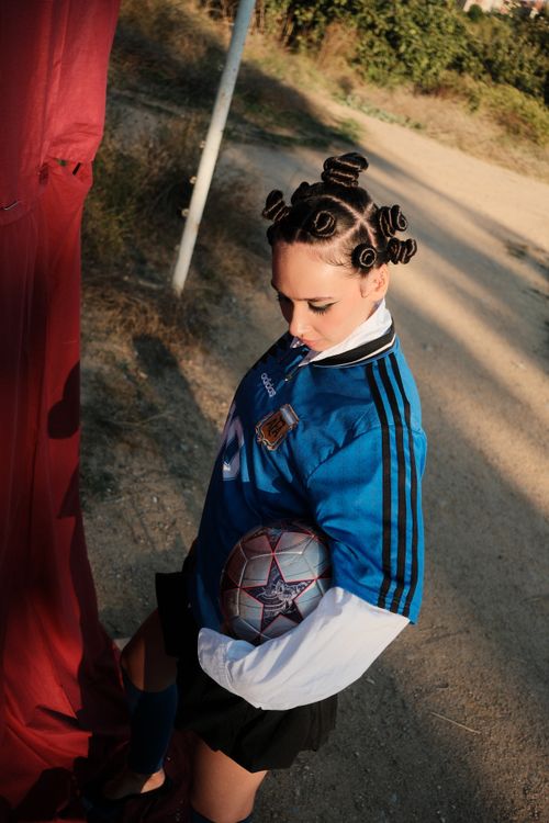 Free Female soccer player with unique hairstyle holds ball, outdoors. Stock Photo