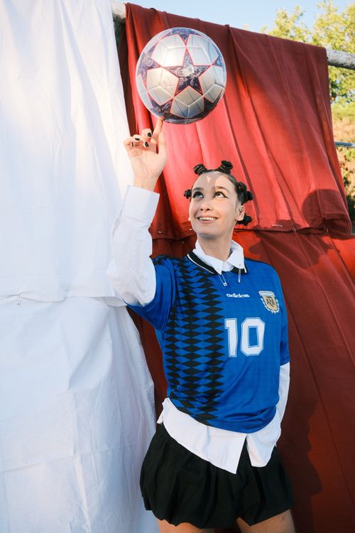 Free Smiling woman in blue jersey spins soccer ball on her finger outdoors, showcasing skill and joy. Stock Photo