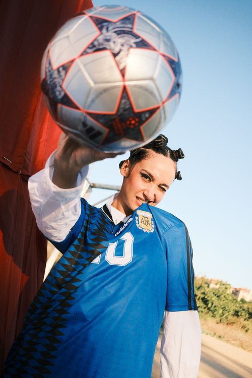 Free A dynamic image of a young soccer player holding a ball towards the camera outdoors. Stock Photo