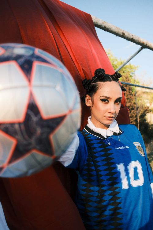 Free Young woman in sports gear, posing with soccer ball outdoors. Stock Photo