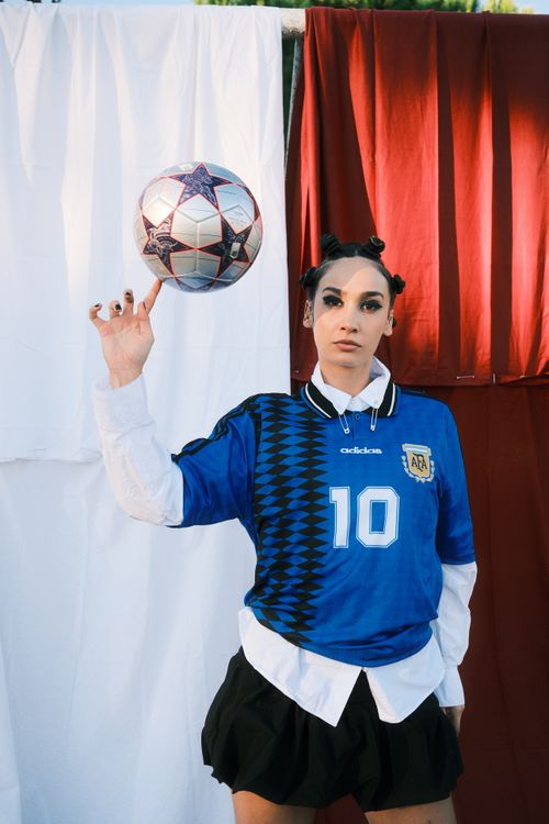 Free A female soccer player skillfully balancing a football against a colorful backdrop. Stock Photo