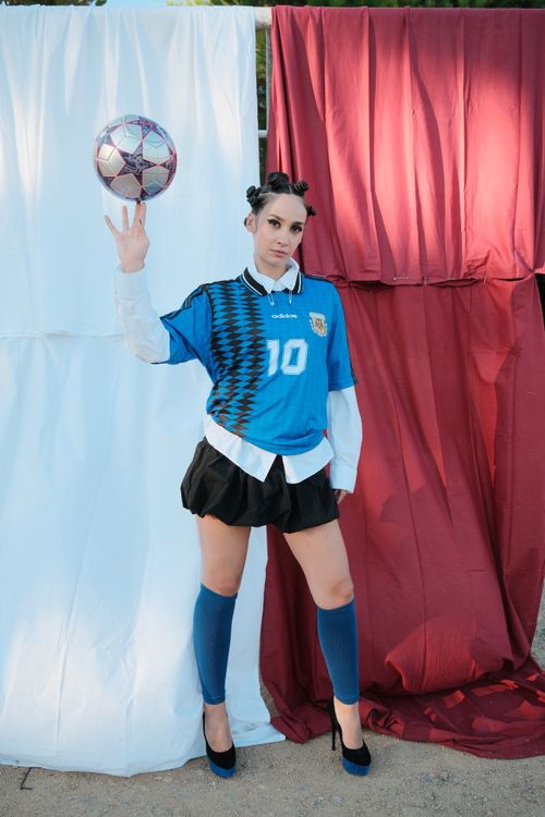 Free Woman standing outdoors in soccer kit with a ball, against a colorful backdrop. Stock Photo