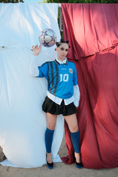 Free Young female soccer fan posing with ball against colorful backdrop. Stock Photo