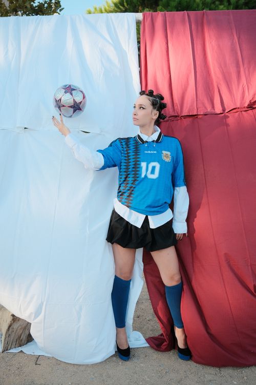 Free Female soccer fan in blue jersey against colorful backdrop holding a football. Stock Photo