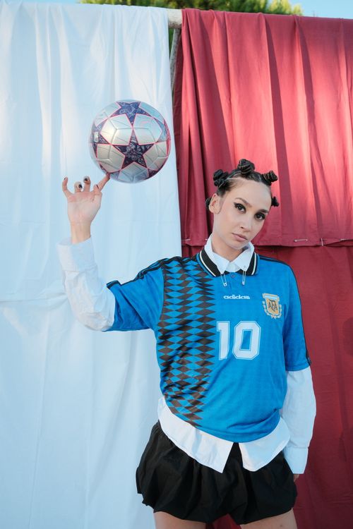 Free Portrait of a woman in an Argentina soccer jersey spinning a ball outdoors. Stock Photo