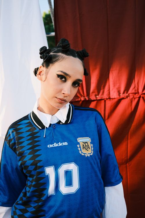 Free A woman in a blue sports jersey poses stylishly outdoors, embodying modern fashion. Stock Photo