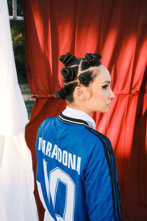 Free Woman wearing blue soccer jersey with a unique hairstyle, captured with creative lighting. Stock Photo