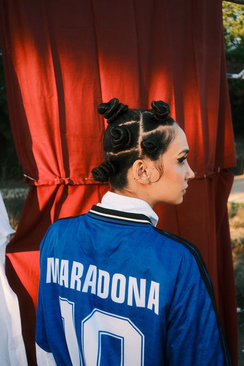 Free Woman with unique hairstyle and Maradona jersey posing outdoors. Stock Photo