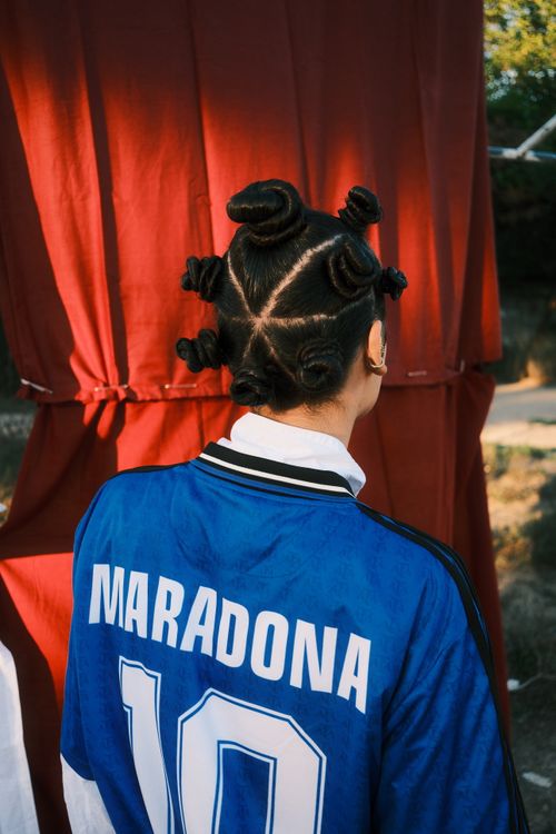 Free Person with unique braided hairstyle wearing a Maradona jersey outdoors. Stock Photo