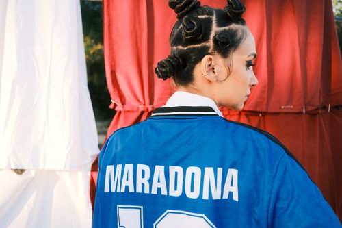 Free A woman with an artistic hairstyle in a blue sports jersey outdoors, highlighting fashion and cultural style. Stock Photo