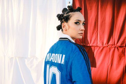Free Portrait of a stylish woman in a blue jersey with bantu knots, exuding confident urban fashion. Stock Photo