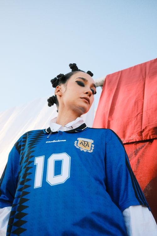 Free Artistic portrait of a person in a blue football jersey with unique hairstyle outdoors. Stock Photo