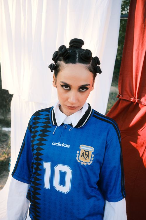 Free Stylish woman in Argentina football jersey posing outdoors with striking hairstyle. Stock Photo