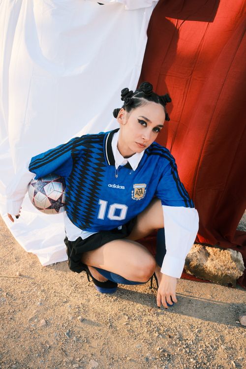 Free A young woman poses outdoors in a sports jersey holding a soccer ball, exuding confidence. Stock Photo