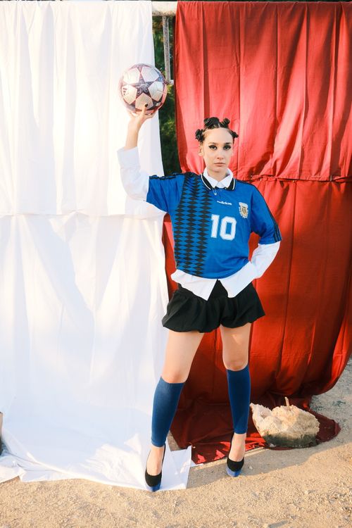 Free Young adult woman posing with a soccer ball in a stylish sports outfit, exuding confidence. Stock Photo
