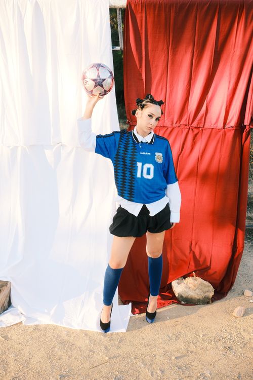 Free A stylish female soccer player in a blue jersey poses with a soccer ball outdoors. Stock Photo