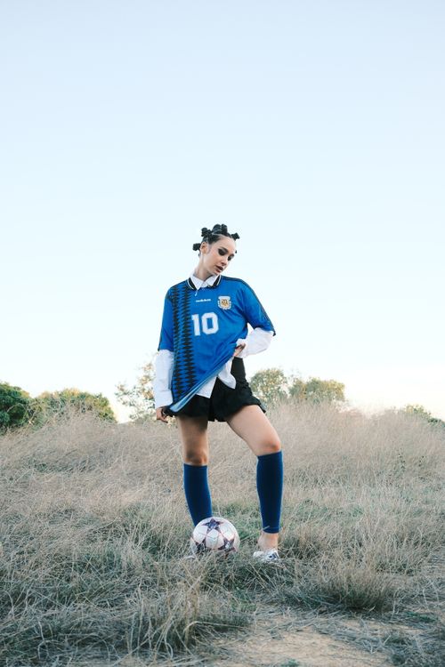 Free Confident young woman in soccer kit posing with ball on a grassy field. Stock Photo