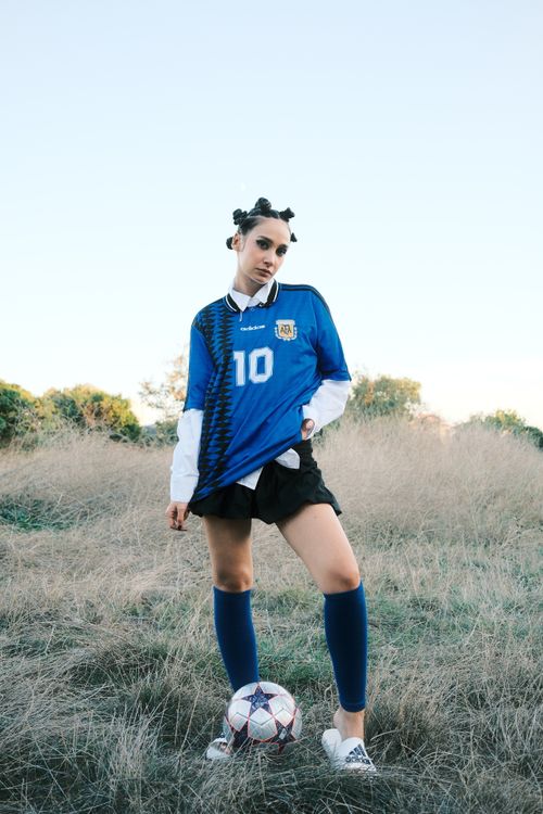 Free A young woman poses in soccer attire, standing confidently on a sunny outdoor field. Stock Photo