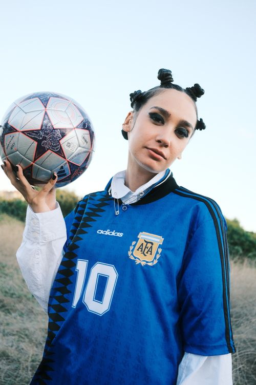 Free Confident young soccer fan in team jersey holding a ball outdoors, showing team spirit. Stock Photo