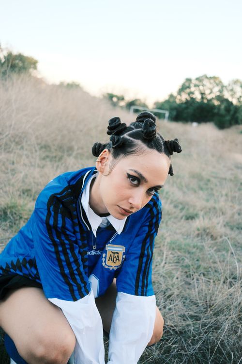 Free Sporty young woman in blue jersey with braided hairstyle posing in a field. Stock Photo