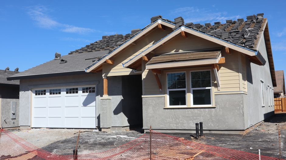 A newly built modern house under construction with garage and roof work.