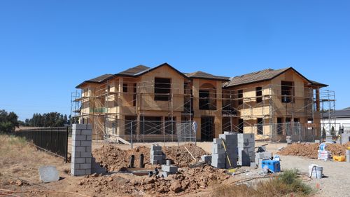 Free Wooden frame house under construction with scaffolding and building materials. Stock Photo
