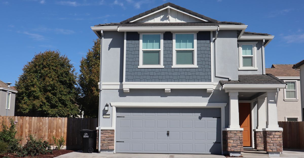 A stylish two-story suburban house with blue siding and a double garage on a sunny day.