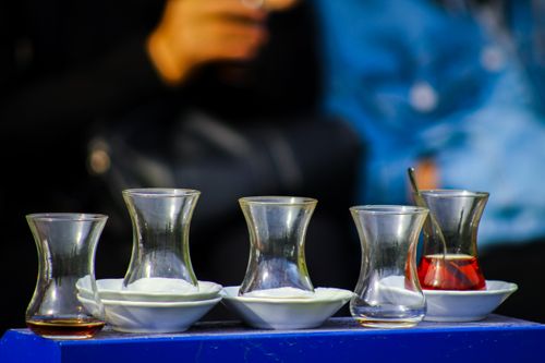 Free Empty glass tea cups on a table outdoors with blurred people in the background. Stock Photo