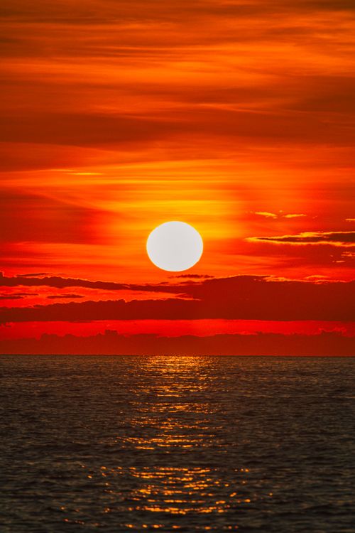 Free Capture of a vibrant sunset over the ocean at Cửa Tùng, Vietnam, reflecting vivid hues in the water. Stock Photo